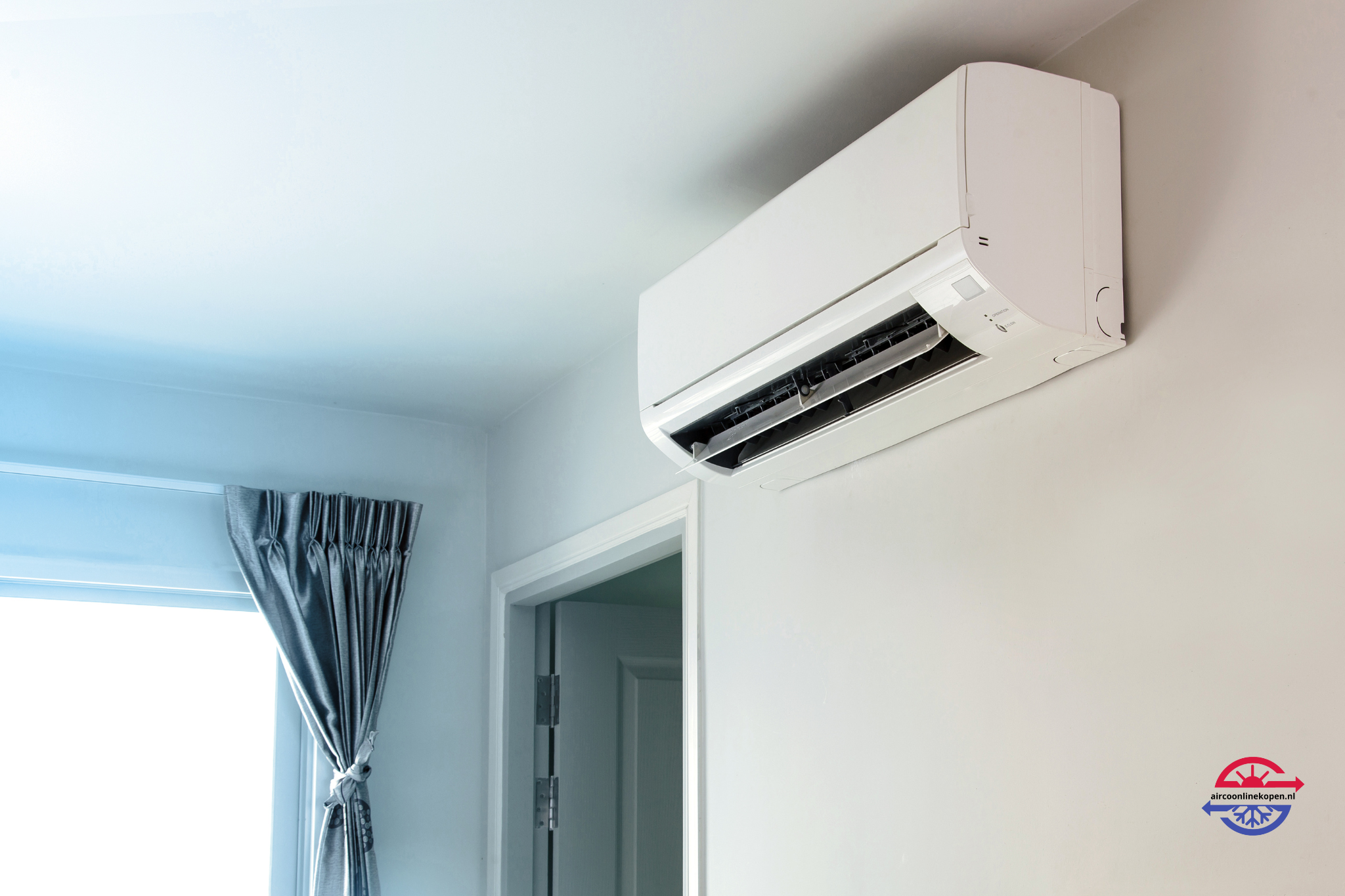 Witte split airco gemonteerd aan wand boven deur in een lichte kamer