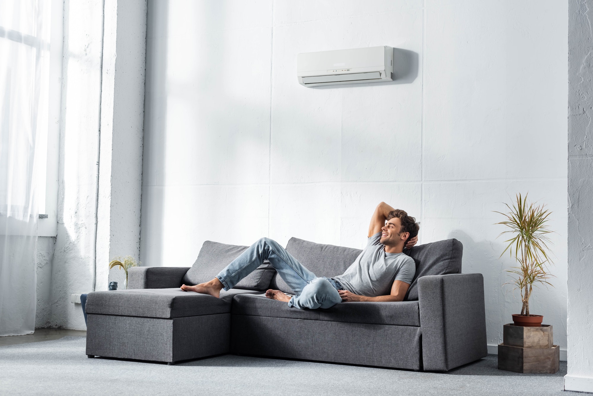 Man ligt gefrustreerd op de bank onder een ongebruikte airco zonder installatie