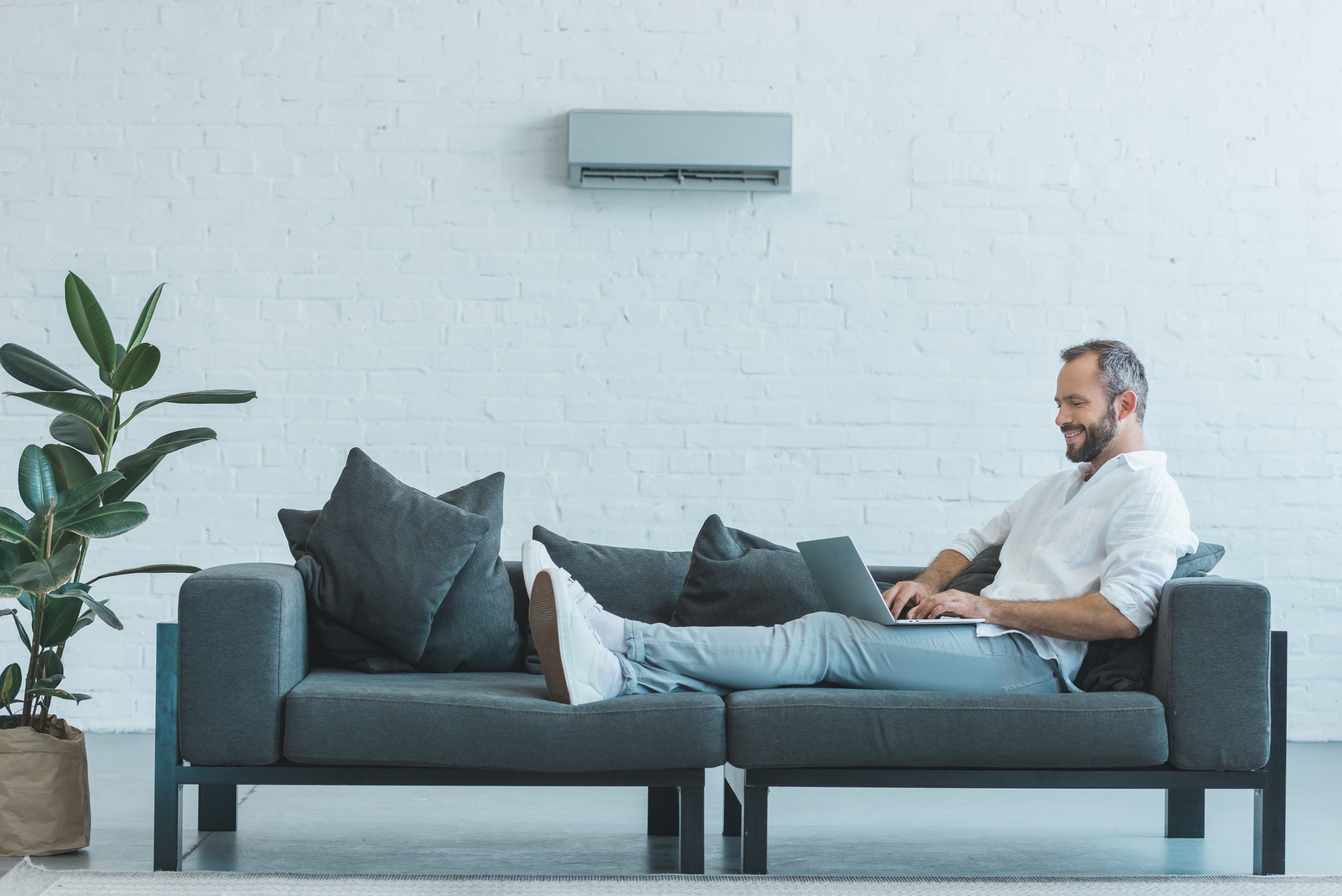 Man ligt ontspannen op de bank dankzij werkende airco via Aircoonlinekopen.nl